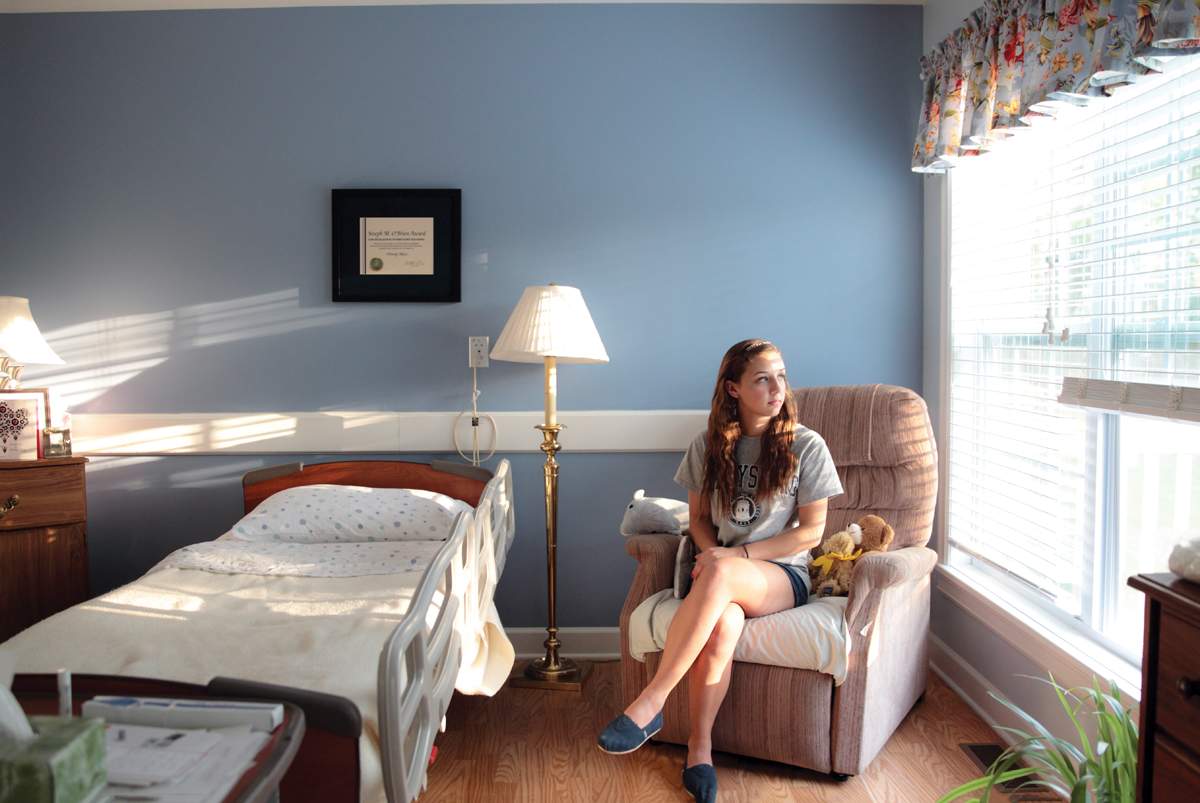 student sitting in empty room where a hospice patient she took care of used to stay