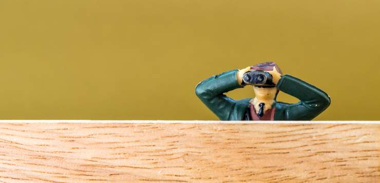 miniature man looking through binoculars