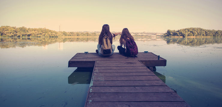 two teenage girls hanging out on dock