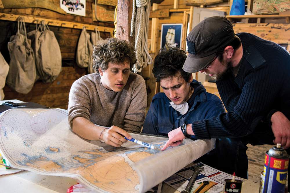 Sea School instructors plan sailing route on map