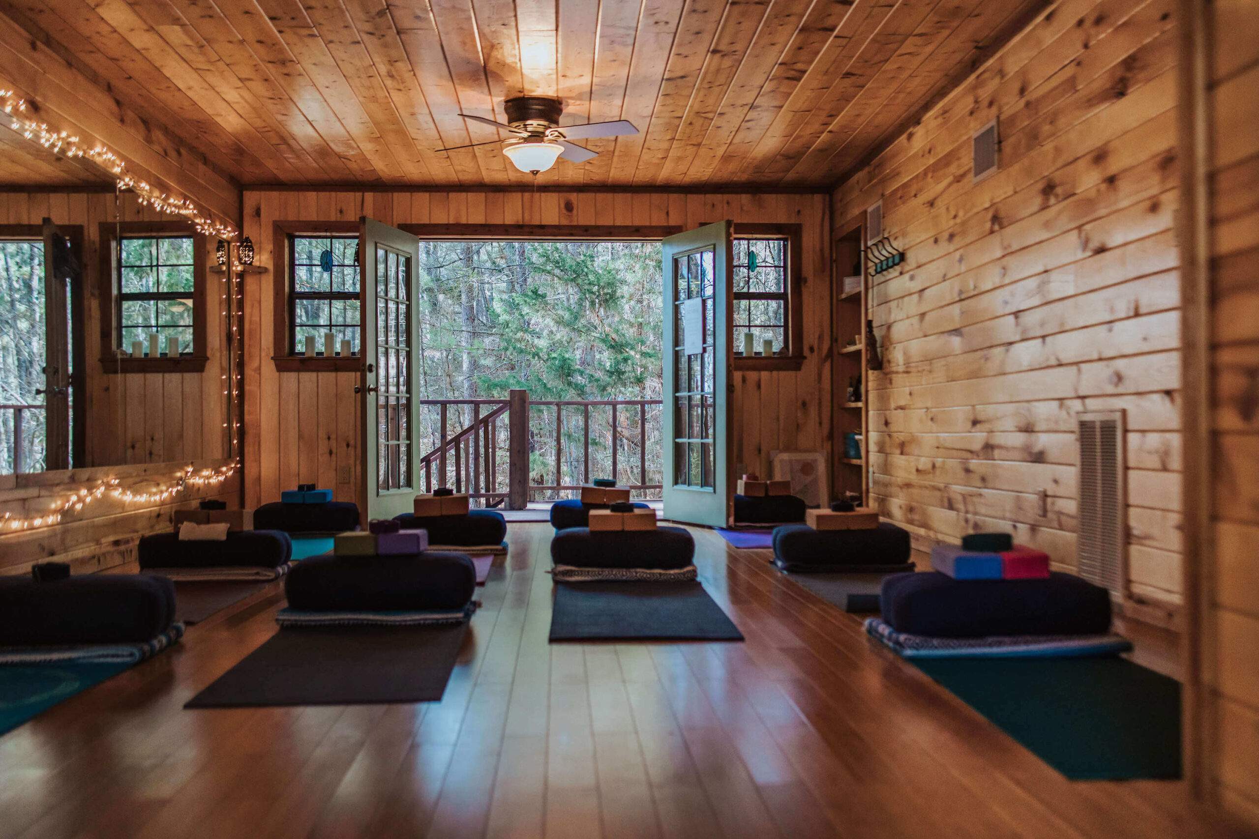 A cozy wooden yoga studio with mats, bolsters, and open doors for grounding practices under the serene Harvest Moon.