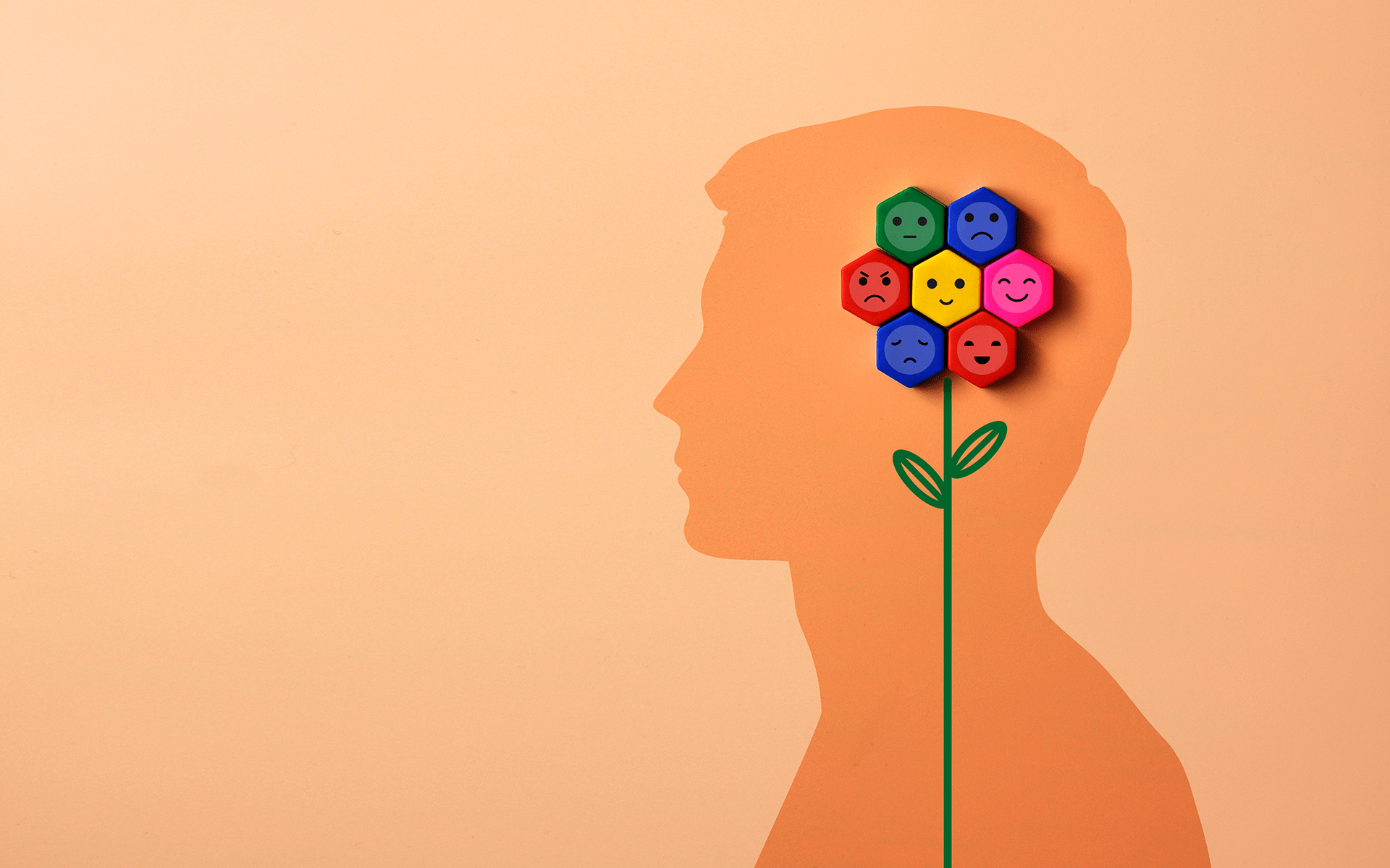 A 12-Minute Meditation to Notice, Shift, Rewire—Orange illustration of a man's profile silhouette with a flower growing up over top of the silhouette and each petal is an octagon with a face expressing a different emotion.