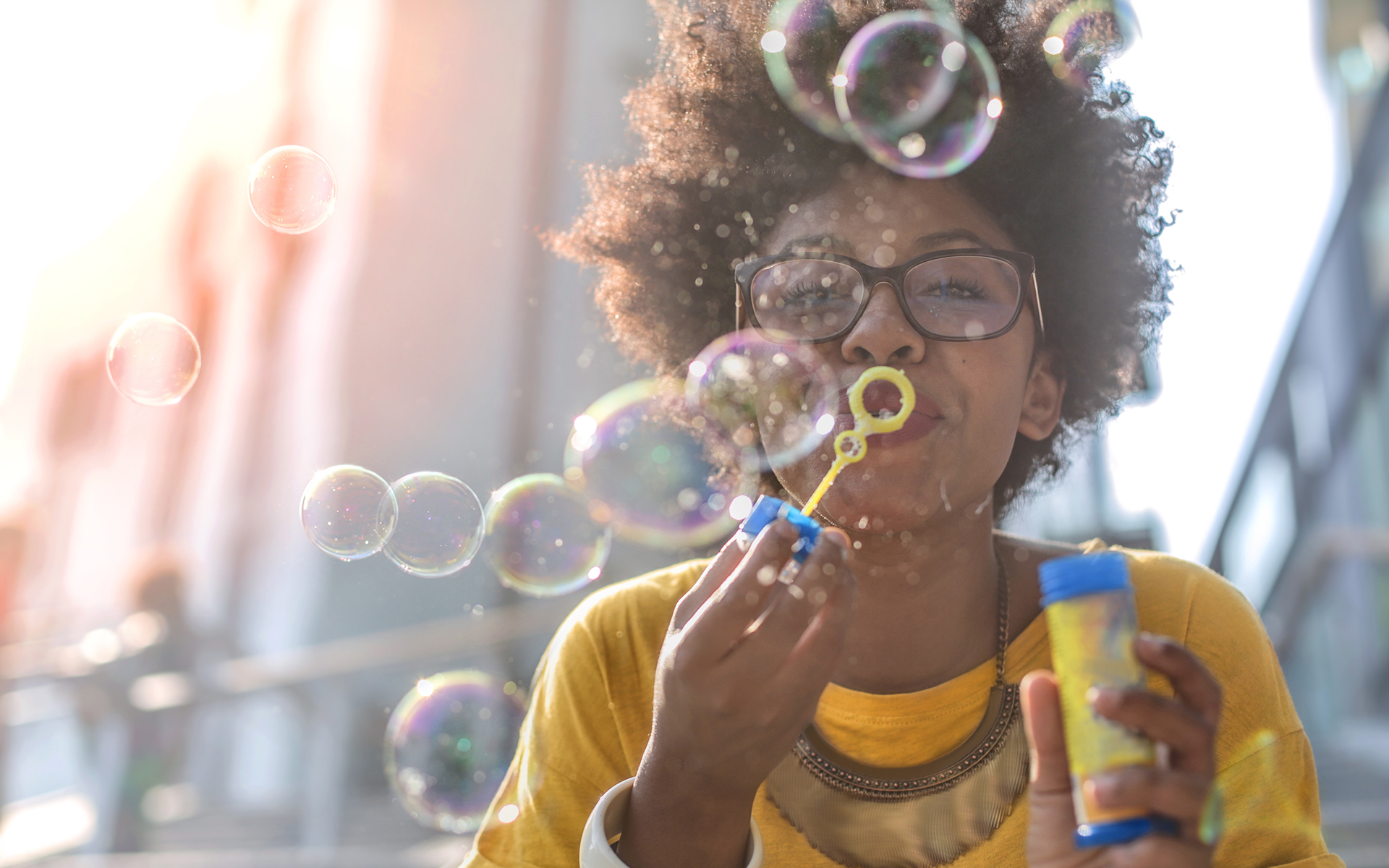 A Practice to Reclaim Your Joy - A Black woman blows soap bubbles outdoors