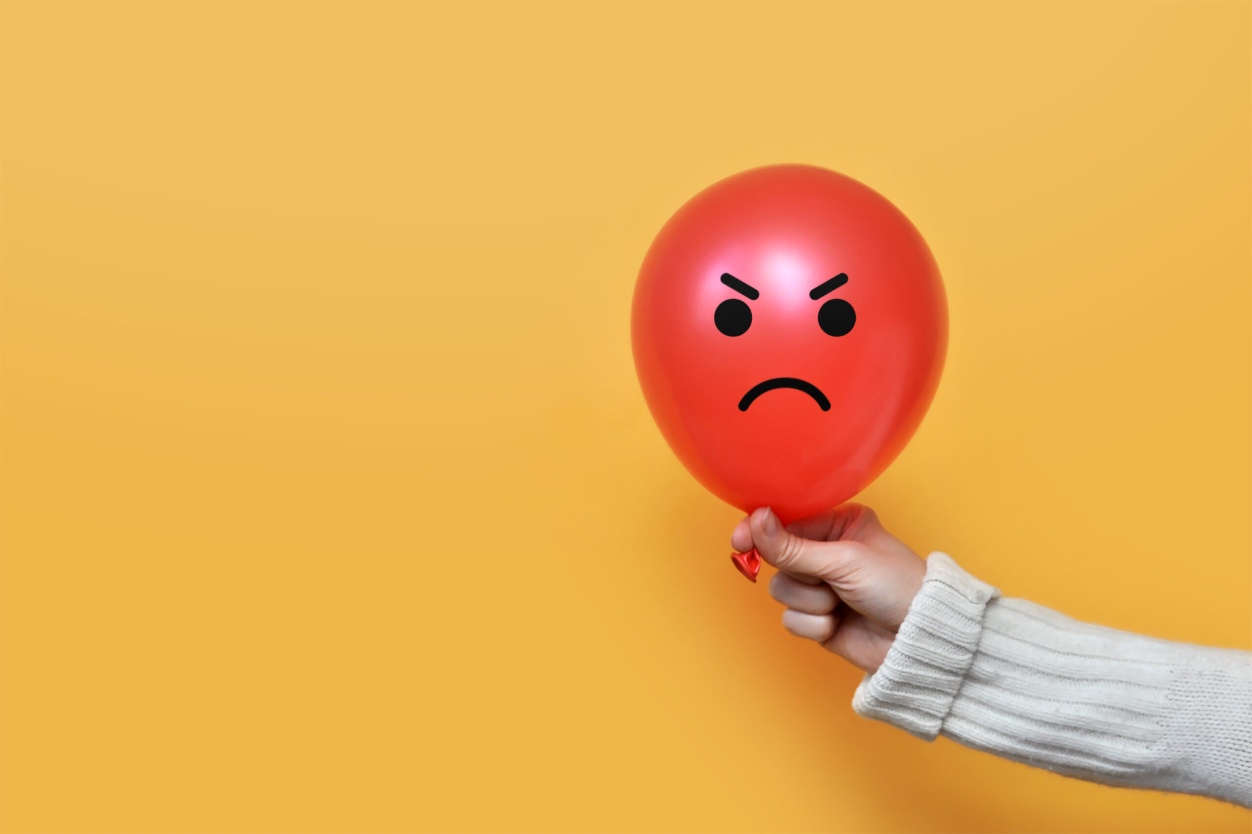 What to do After an Angry Outburst—Photo of a red balloon with an angry face on it held in the hand of a woman with a grey sweater on.