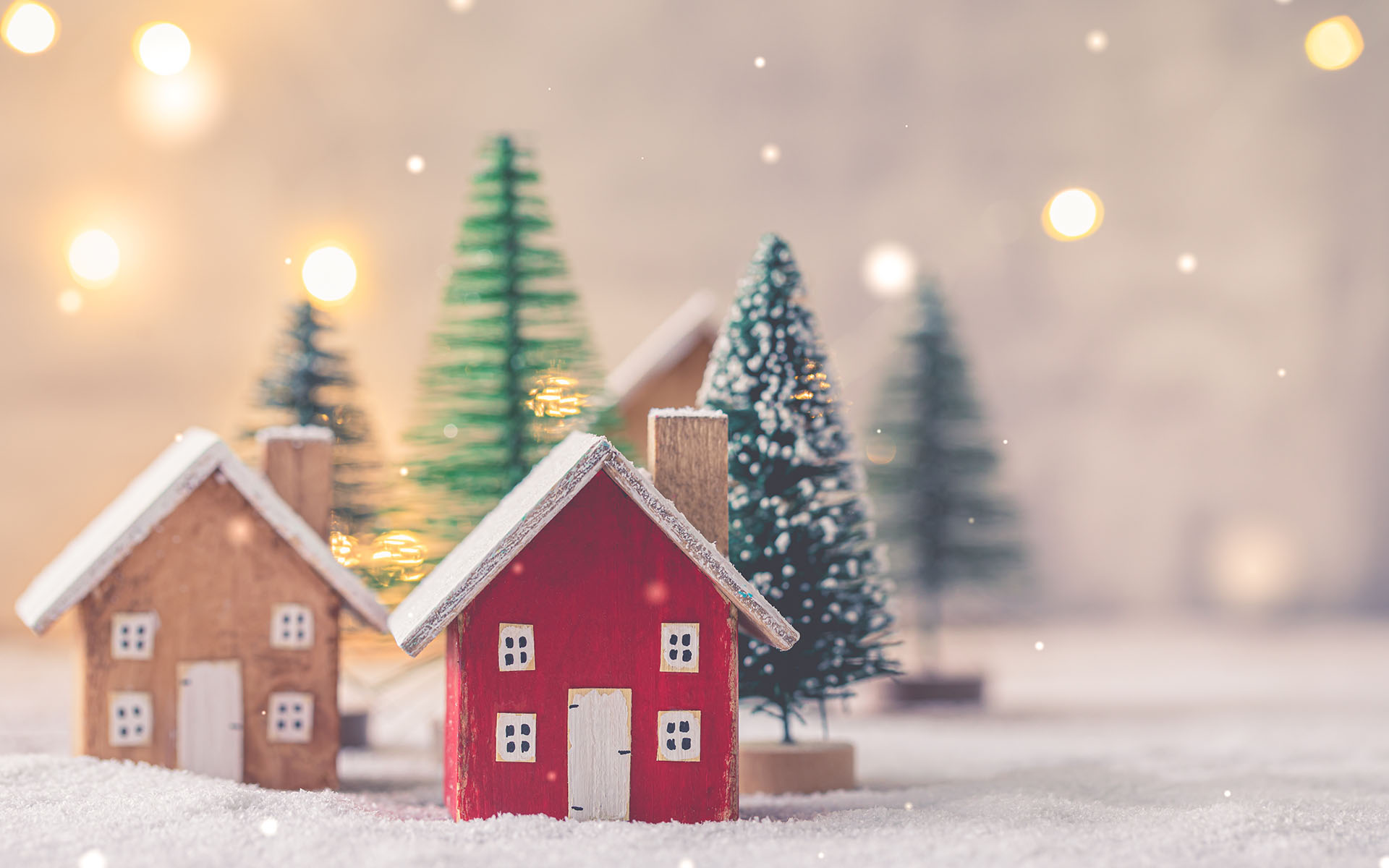Home for the Holidays: A Self-Love Practice -Miniature wooden houses on the snow over blurred Christmas decoration background, toned, postcard concept