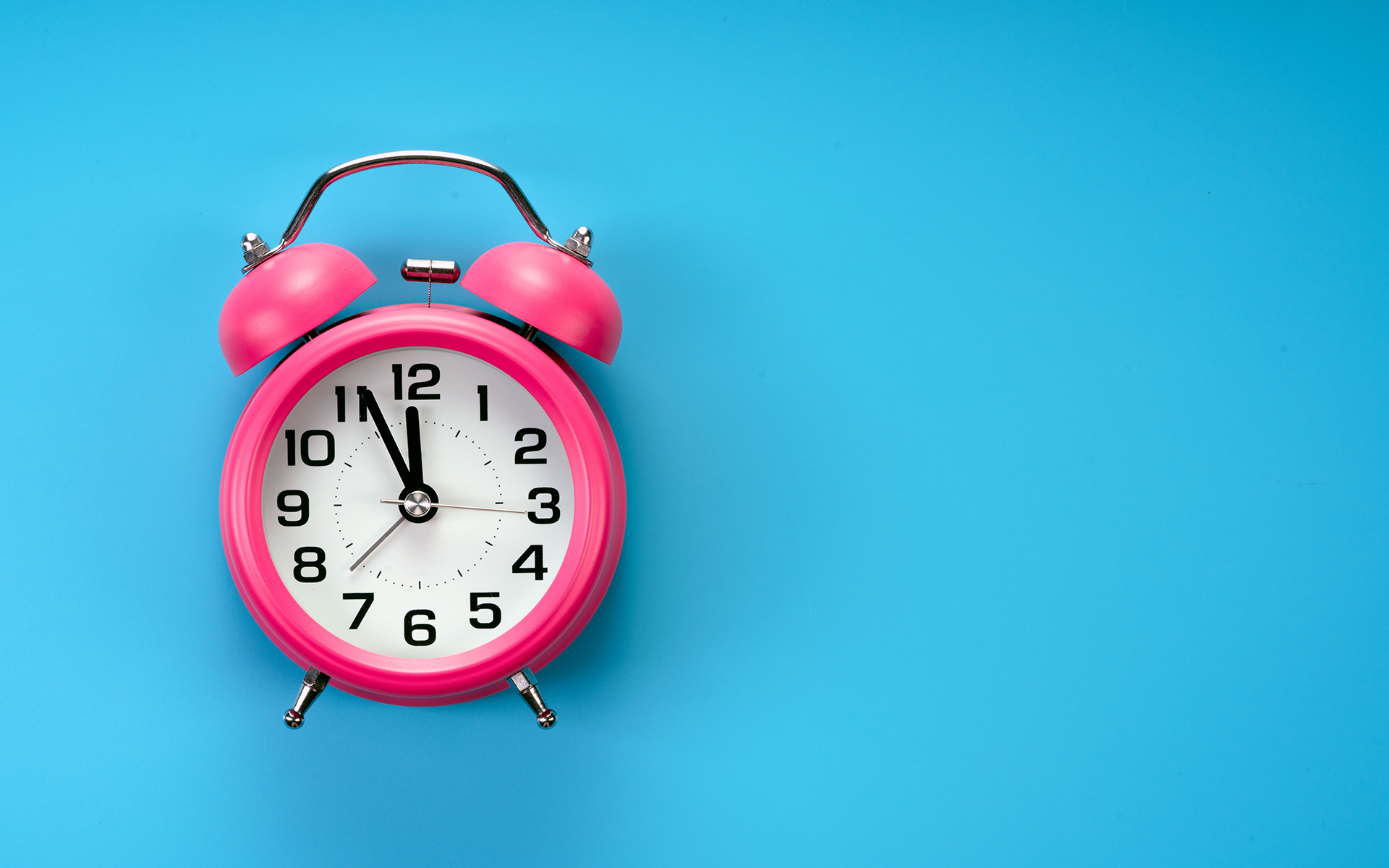 How Our Perception of Time Shifts (When We Are Present)—A pink alarm clock is over a blue background.