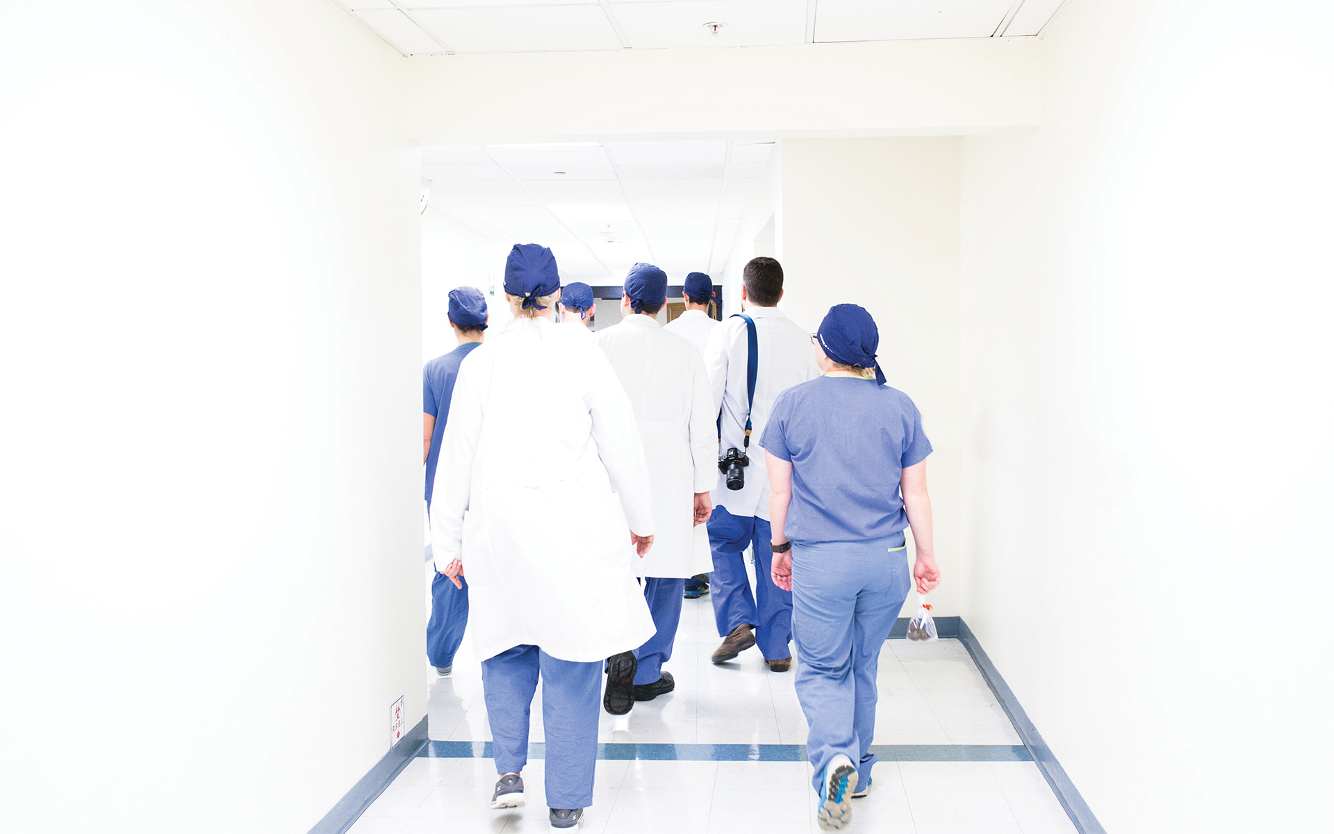 How Integrity Can Heal Burnout - A group of doctors, nurses, and other healthcare workers walking down a hallway in scrubs and uniforms