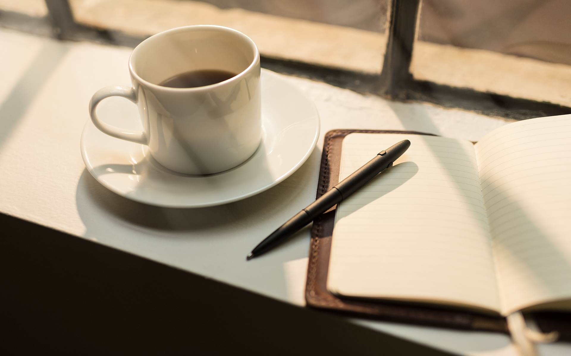 Journaling prompts to help you let go of limiting habits - Image of an open journal and coffee cup on a desk