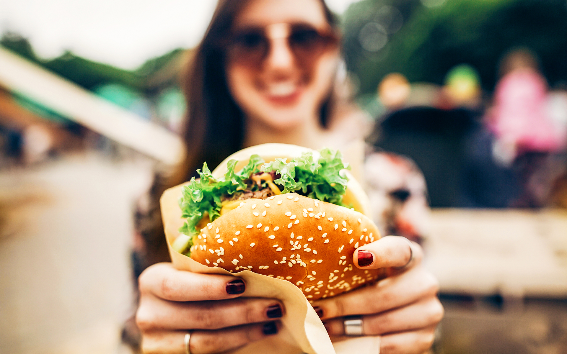 Ways to Practice Mindful Eating - Image of a woman holding a hamburger