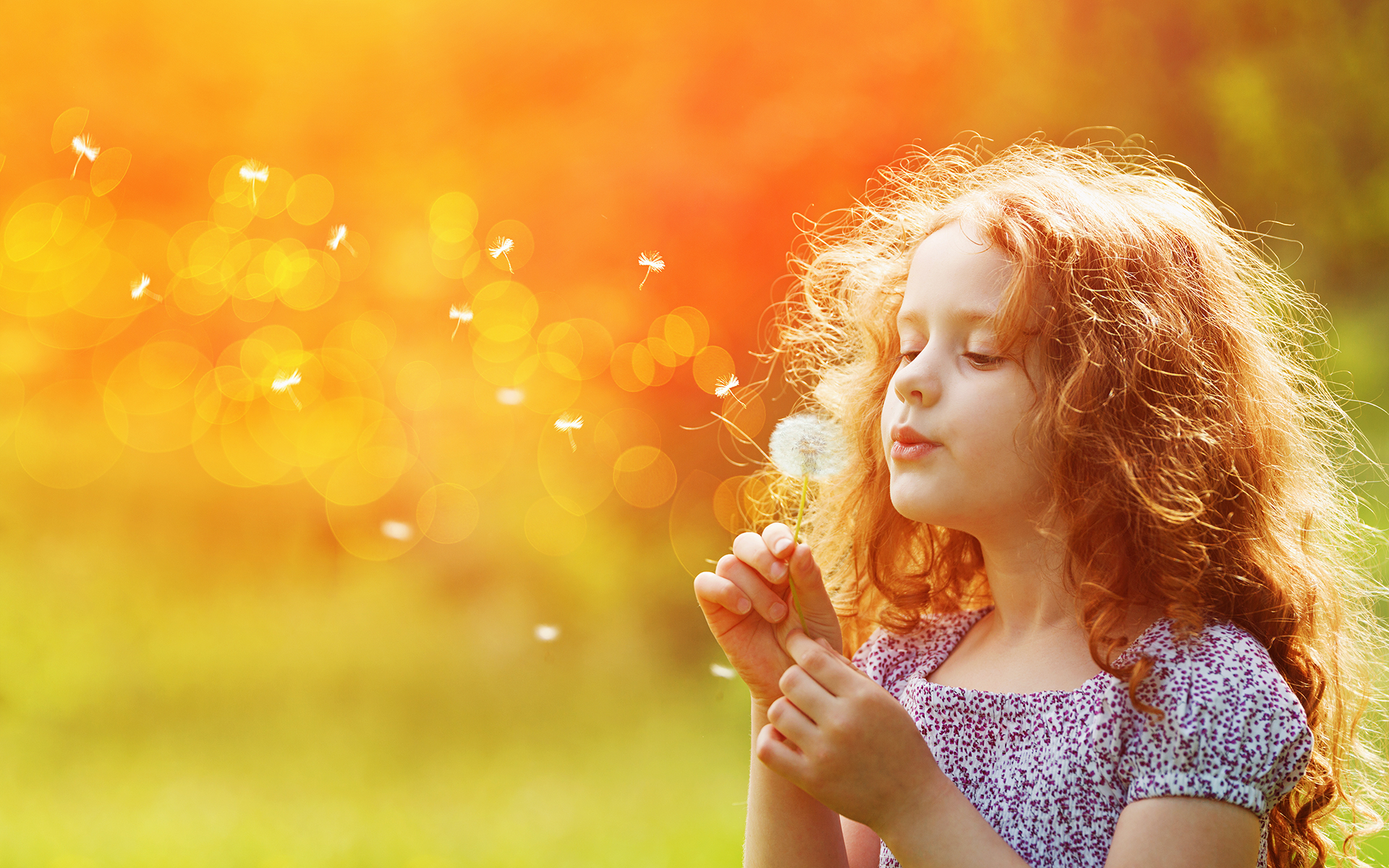Research Shows Mindful Breathing Can Help Kids Find Calm—Photo of a red-headed little girl outdoors blowing the seeds of a dandelion.
