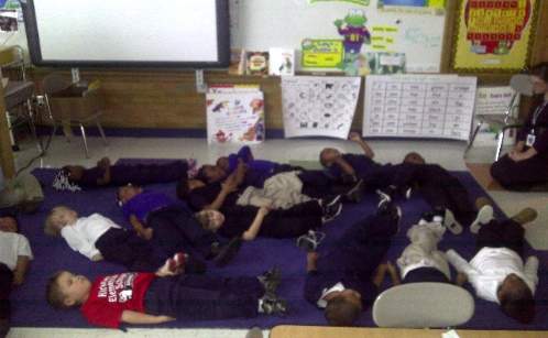 A mindful group of children laying on the floor in a classroom, embracing their inner angels.