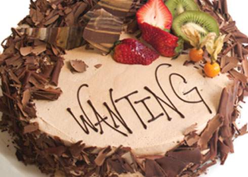A chocolate cake with the word waiting written on it.