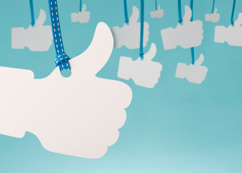 A bunch of thumbs up signs hanging from strings on a blue background.