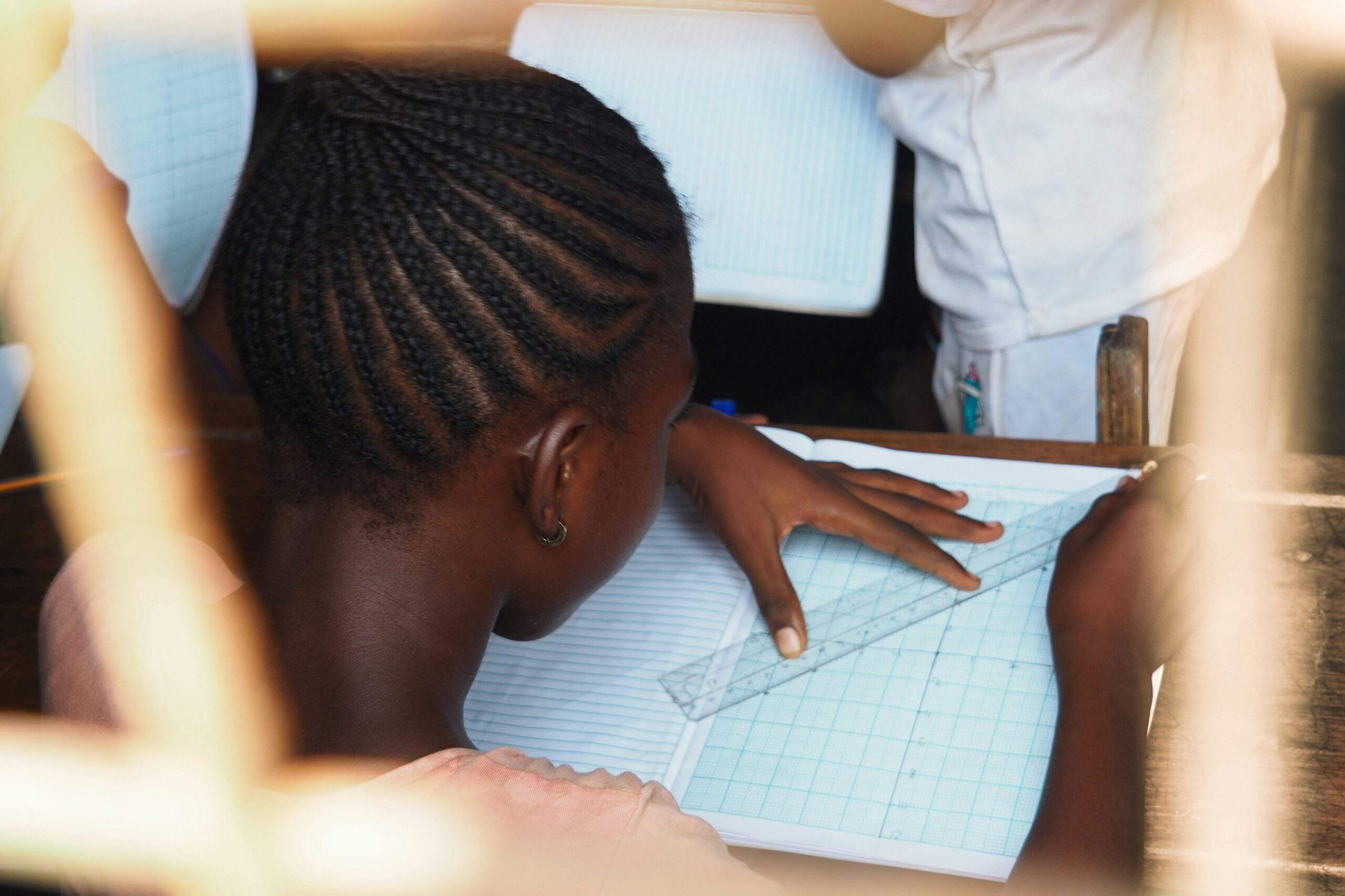 A Back-to-School student uses a ruler and pencil to draw lines in a grid notebook, practicing focus from their Mindfulness Toolkit.