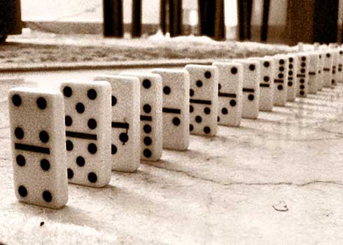 A line of dominoes on a concrete floor.