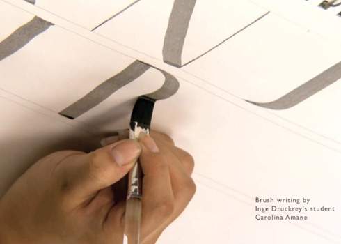 A person is writing a letter on a piece of paper.