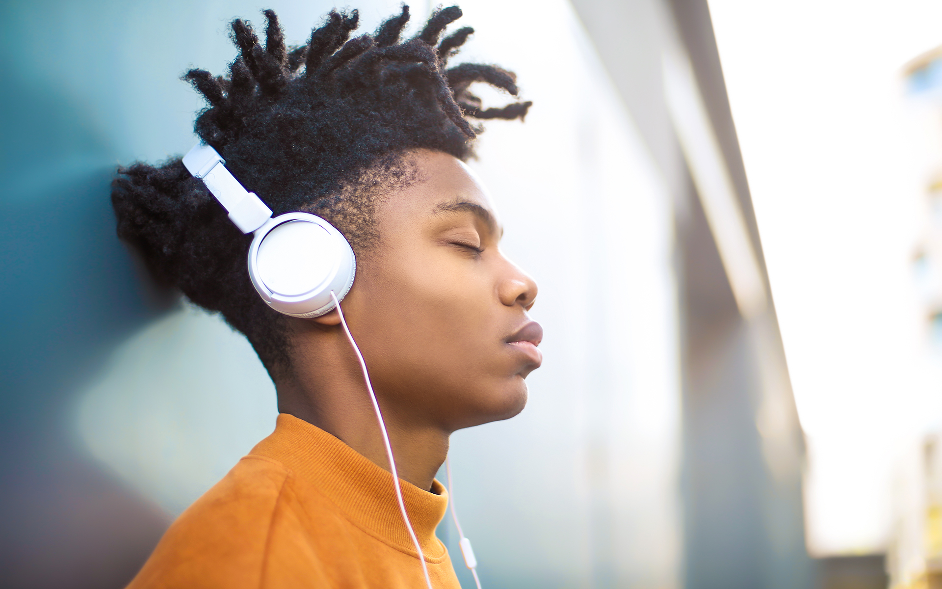 A Guided Meditation for Patience and Resolve - Young Black man listening to a guided meditation with white headphones