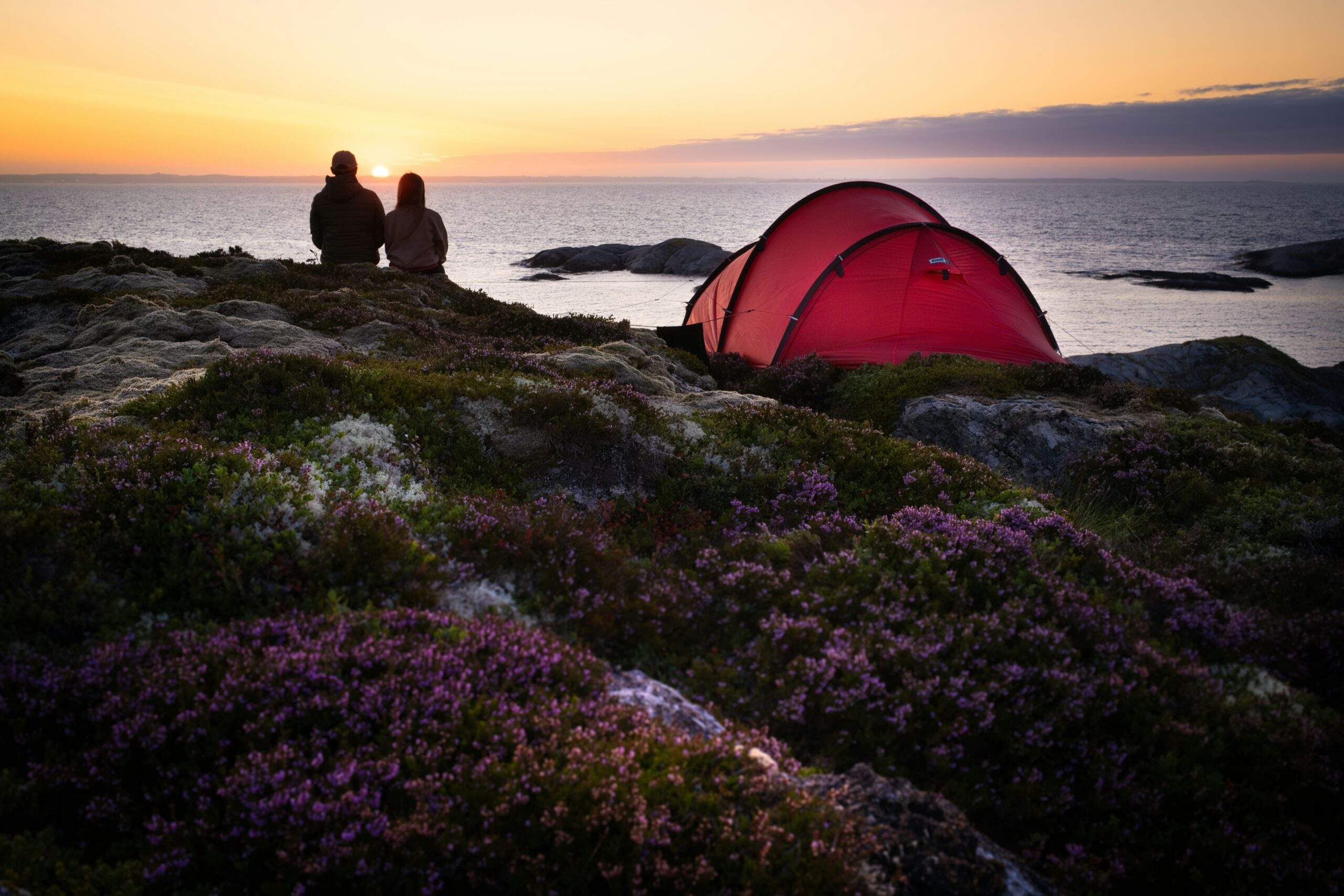Two people camping and watching the sunset, practicing present-moment awareness.