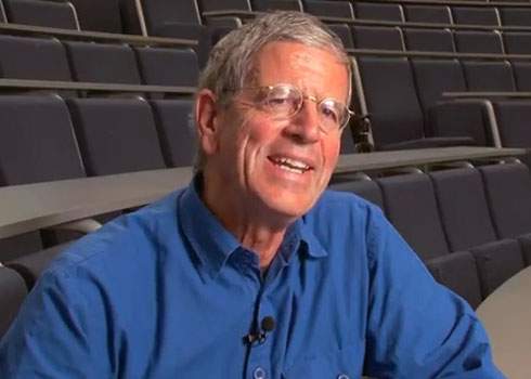 A man in a blue shirt sitting in an auditorium.