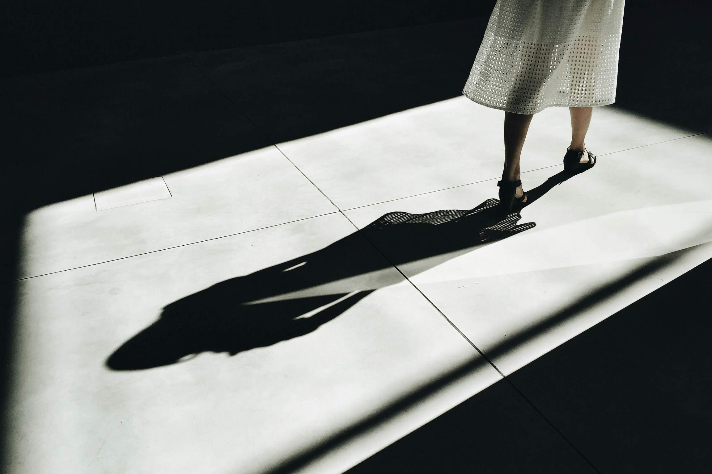 Image of woman walking while a beam of light casts a shadow behind her. Image meant to convey the concept of the predictive shadow.