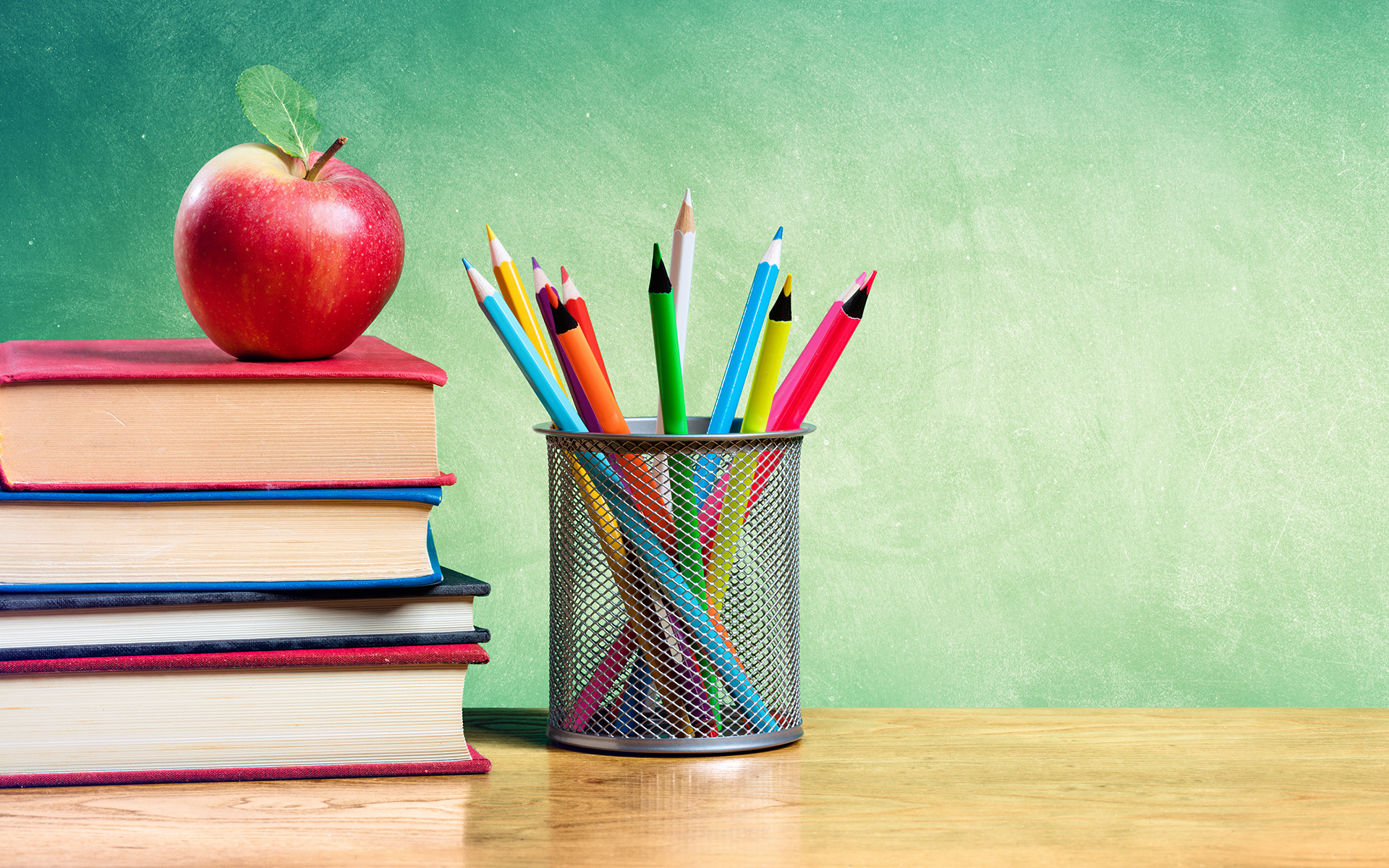 Photo of Apple On Stack Of Books With Pencils And Blank Chalkboard