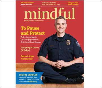 A smiling man in a police uniform sits cross-legged on the cover of Mindful magazine. The cover story headline reads 