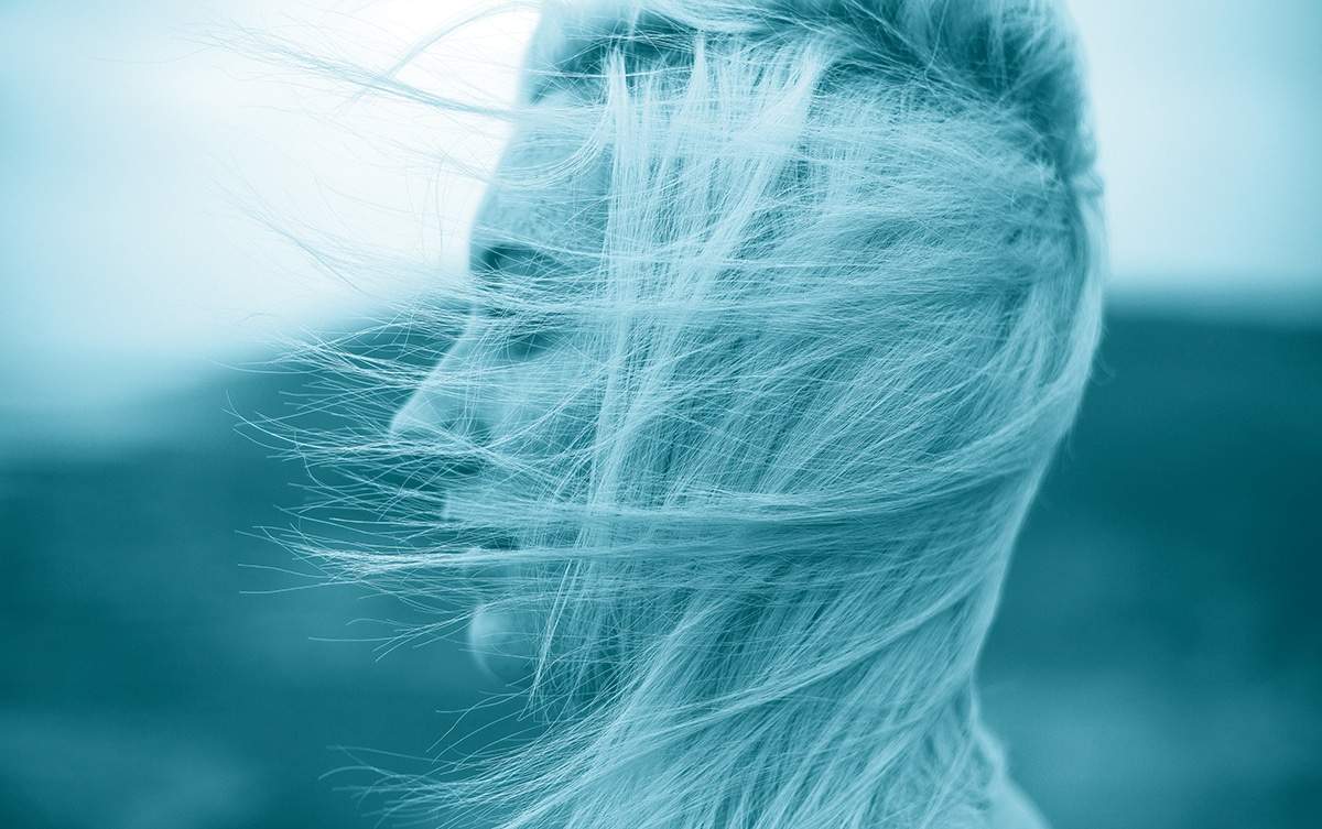 women facing away from the wind with her eyes closed