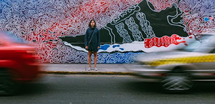 woman standing on sidewalk in front of colorful mural