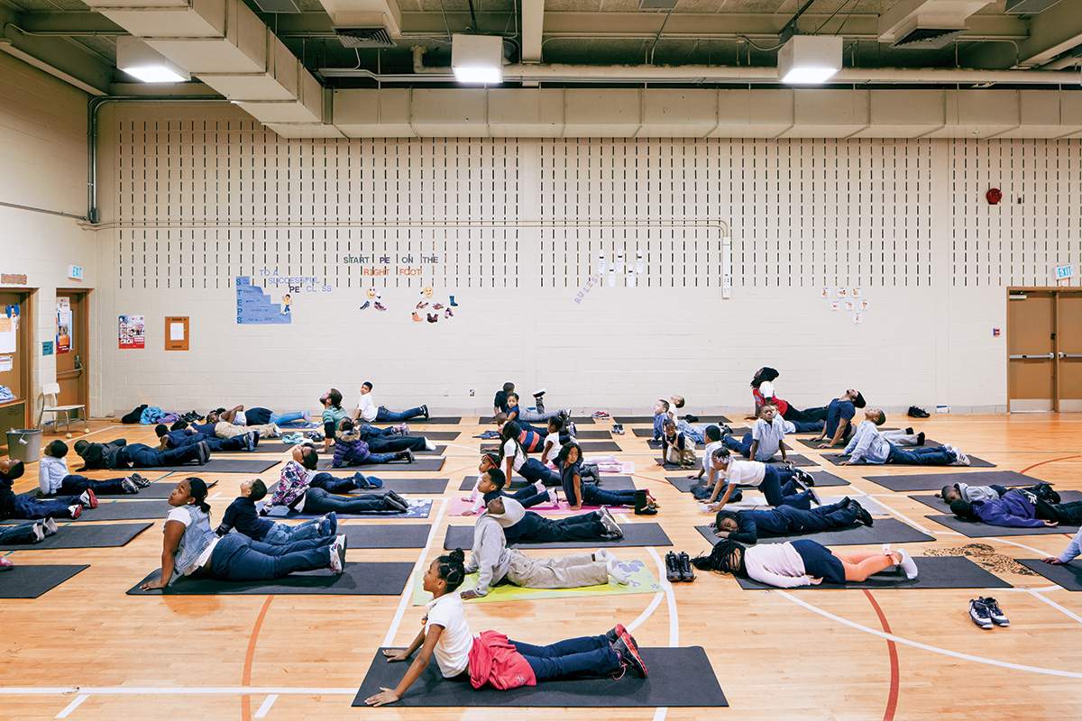 Children practice yoga with Andy Gonzalez (second row, third in from the wall) in the gymnasium of Robert W. Coleman Elementary School in Baltimore.