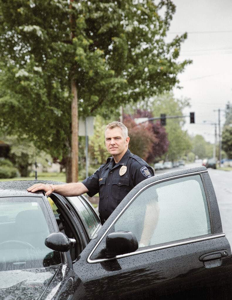 Police officer Rich Goerling standing by car in the rain