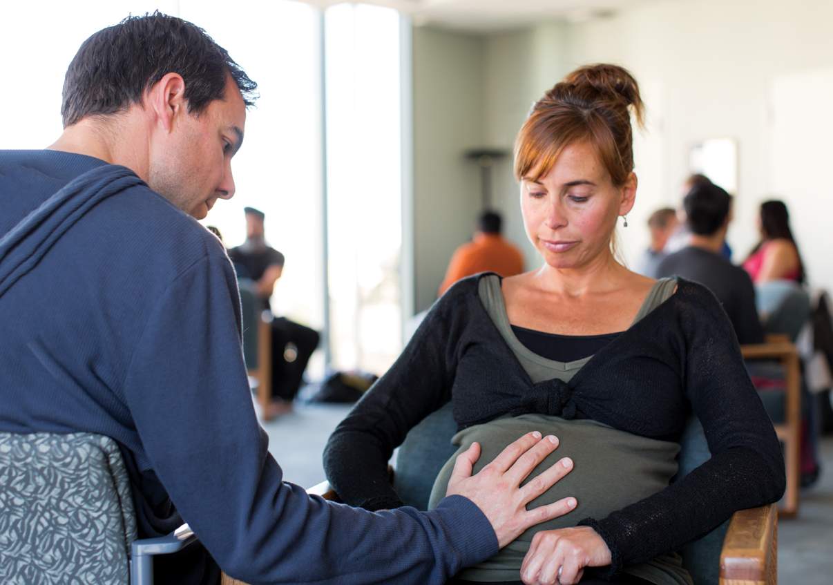 husband helps wife through breathing practice