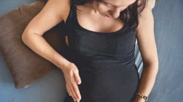 How Your Own Mind Can Reduce the Fear of Giving Birth pregnant woman lying down holding belly