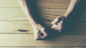 Why Emotional Self-Control Matters person with hands on wooden desk, fists clenched in frustration