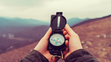The Art of Easing into Change woman holding compass in mountains