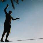 Using Mindfulness to Manage Your Expectations man balancing on tightrope on the beach