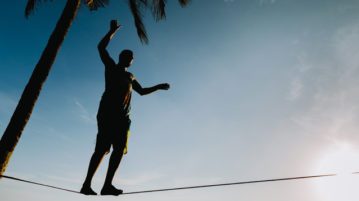 Using Mindfulness to Manage Your Expectations man balancing on tightrope on the beach