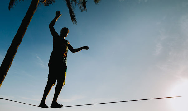 Using Mindfulness to Manage Your Expectations man balancing on tightrope on the beach