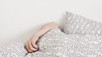 Tame Feelings of Shame with this 10-Minute Practice arm laying over blanket, face covered